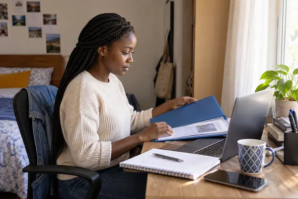 A young woman preparing her CV at a desk at home